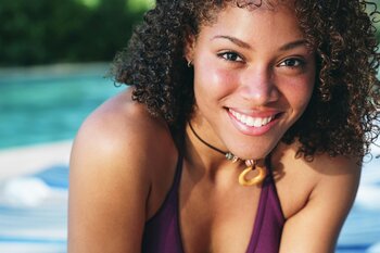 African American girl smiling by pool in swimsuit nice smile straight teeth. Invisalign in Northvale, NJ and Manhattan, NY